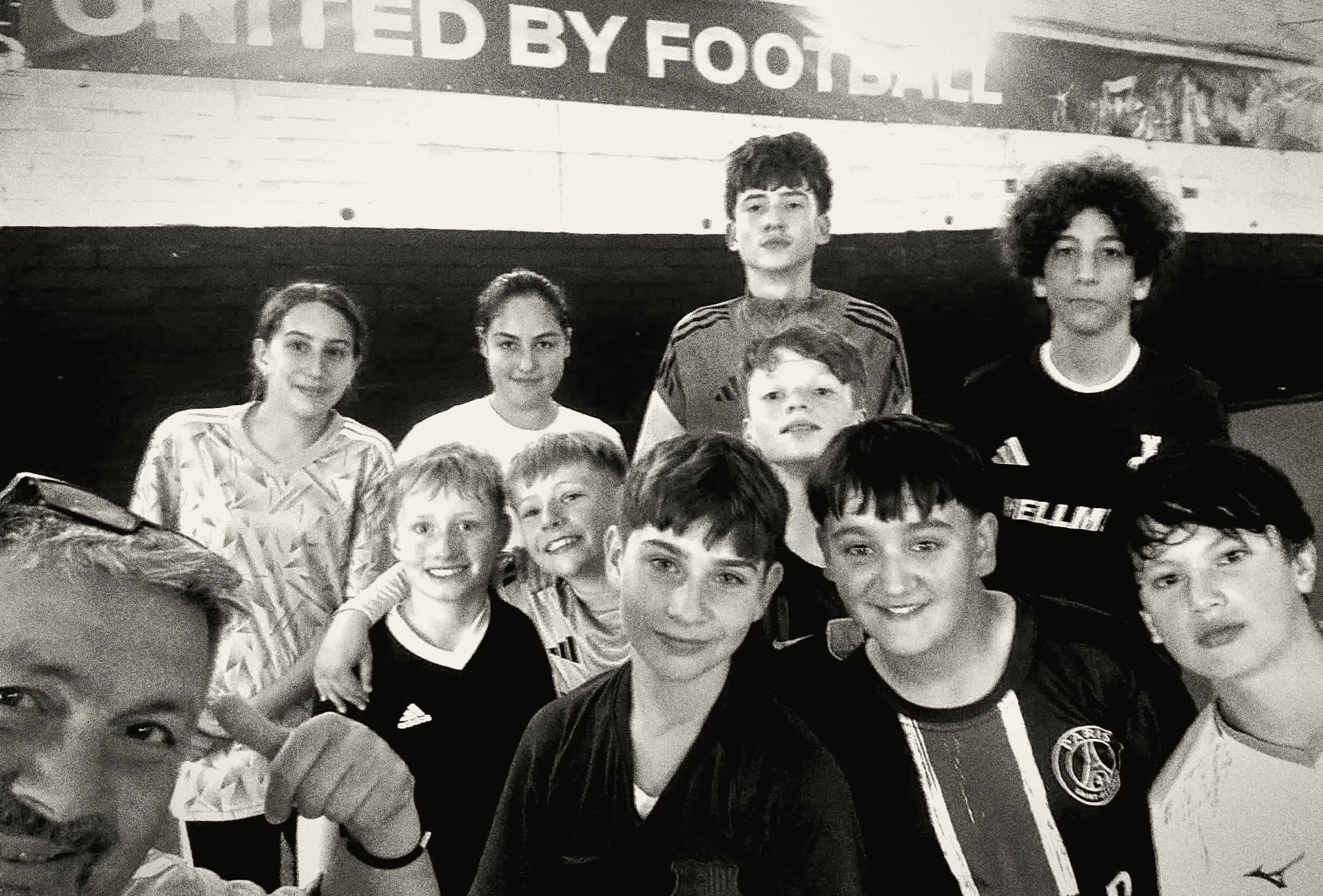 Maurizio Mastroieni mit einer Gruppe Kinder in seiner Halle in Herten, darüber das Banner „United by Football“